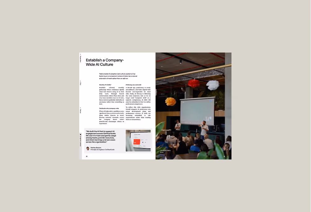 Open book showing a page titled 'Establish a Company-Wide AI Culture' with text and a photo of two speakers presenting to an audience in a modern office decorated with hanging paper lanterns.